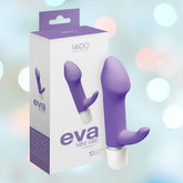 A vibrantly colored product photo features the VeDO Eva Mini Vibrating Clitoral and G-Spot Vibrator - 'Orgasmic Orchid,' a versatile device by VeDO. The purple vibrator is depicted alongside its packaging, showcasing its ergonomic design. The box highlights its 10 vibration modes. The background is a soft focus of multicolored lights.